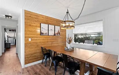 a dining room with a wooden wall and a table and chairs at Relaxing 4 bedroom Mountain Stay in Lake Arrowhead