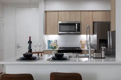 a kitchen with a counter top with two plates and wine glasses at High-End 1BR Oasis | Walk to Ocean & 3rd Street in Los Angeles