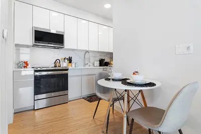 a kitchen with white cabinets and a table and chairs at Laugh in the Lap of Luxury In SM * FREE Parking * in Los Angeles