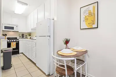 a white kitchen with a table and a refrigerator at Santa Monica's Prestige Place *Steps To The Beach* in Los Angeles