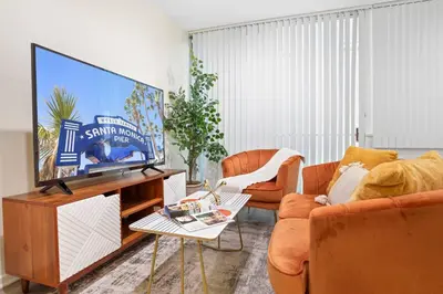 a living room with a flat screen tv and orange chairs at Santa Monica's Prestige Place *Steps To The Beach* in Los Angeles