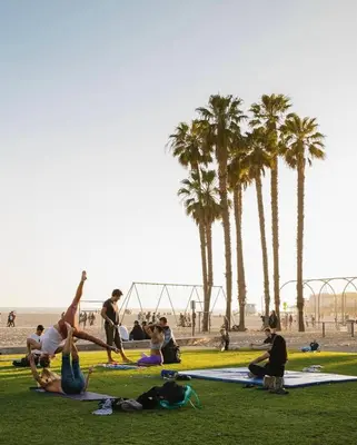 a group of people sitting on the grass at the beach at SoCal Luxurious Apt Steps To The Beach & Pier in Los Angeles