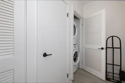 a white laundry room with a washer and dryer at 5-star West Hollywood Living | Modern & Central in Los Angeles