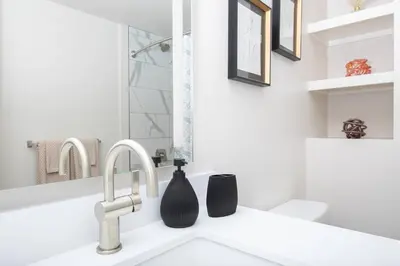 a bathroom sink with a black bottle on it at 5-Star West Hollywood Living | Modern & Central in Los Angeles