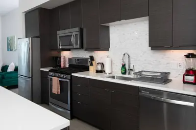 a kitchen with black cabinets and stainless steel appliances at West Hollywood Luxe | 2BR/2BA Resort Style in Los Angeles