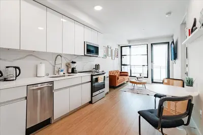 a kitchen with white cabinets and a table and a living room at Santa Monica 1BR apt with Parking in Los Angeles