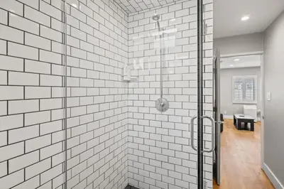 a glass shower in a bathroom with white tiles at Modern 1BR • Steps to Venice Beach in Los Angeles