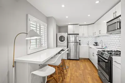 a white kitchen with a counter and a refrigerator at Modern 1BR • Steps to Venice Beach in Los Angeles