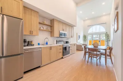 a kitchen with wooden cabinets and a table at The Village Collection with Gym Pool and Spa in Montclair