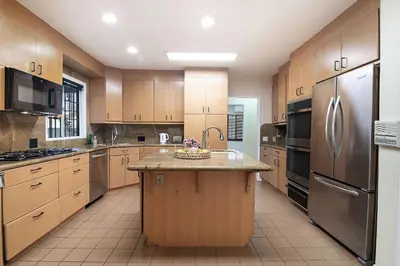 a large kitchen with wooden cabinets and stainless steel appliances at Spacious 4BR Spanish Villa In Hancock Park in Los Angeles