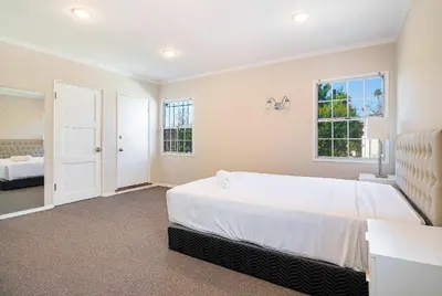 a bedroom with a large bed and two windows at Spacious 4BR Spanish Villa In Hancock Park in Los Angeles