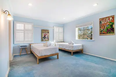 two beds in a room with blue walls and windows at Spacious 4BR Spanish Villa In Hancock Park in Los Angeles