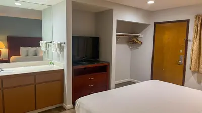 a bathroom with a bed and a sink and a television at Studio 6 Victorville Green Tree Bvld in Victorville