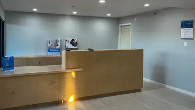 a lobby with a wooden counter with lights on it at Studio 6 Victorville Green Tree Bvld in Victorville