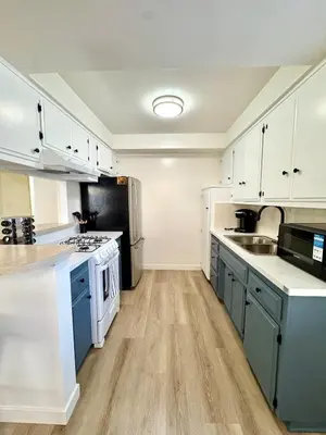 a large kitchen with white cabinets and blue appliances at Private Flat 15 min to Pasadena, DTLA, JPL in Alhambra
