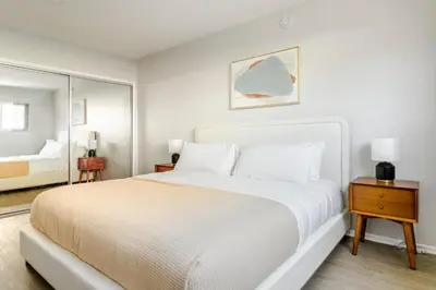 a white bedroom with a large bed and a mirror at Blueground Westwood balcony nr UCLA LAX-1397 in Los Angeles