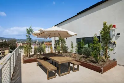 a patio with an umbrella and a table and benches at Blueground East Hollywood rooftop nr Hollywood Bowl LAX-1334 in Los Angeles