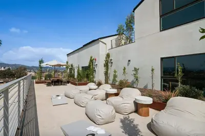 a patio with white chairs and tables and a building at Blueground East Hollywood rooftop nr Hollywood Bowl LAX-1334 in Los Angeles