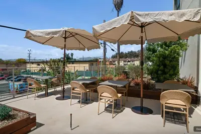 a patio with tables and chairs and umbrellas at Blueground East Hollywood rooftop nr Hollywood Bowl LAX-1334 in Los Angeles