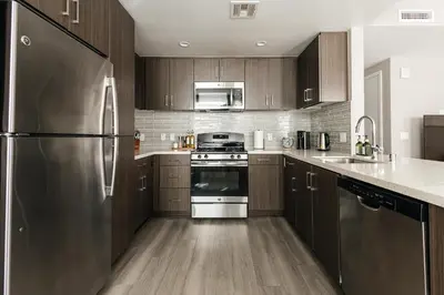 a kitchen with wooden cabinets and a stainless steel refrigerator at Excellent Town Home 2BR in WEHO Parking,Gym,Pool in Los Angeles