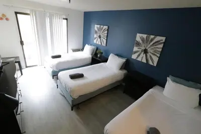 a room with three beds and a blue wall at 3 beds Apart in Beverly Hills in Los Angeles