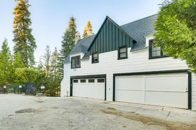 a white house with two garage doors at Steps to Lake Arrowhead Village Chic Apartment in Lake Arrowhead