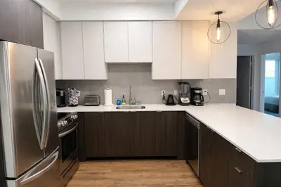 a kitchen with white cabinets and a stainless steel refrigerator at Penthouse Corner 3 Bedroom Condo with Large Private Balcony and Parking in Los Angeles
