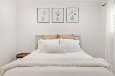 a bedroom with a white bed with four pictures on the wall at Goode HOMES Stunning Home w/ Beautiful Backyard in Santa Clarita