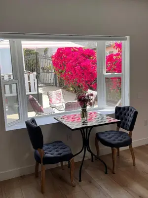 a table and chairs in front of a window with pink flowers at Newly Built Private Guest House in Glendale