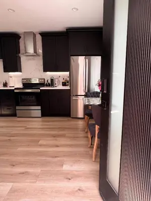 a kitchen with black cabinets and a wooden floor at Newly Built Private Guest House in Glendale