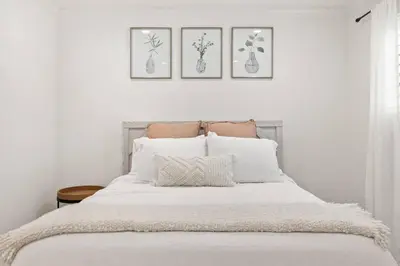 a bedroom with a white bed with three pictures on the wall at GOODE.HOMES | Luxury Home w/ Beautiful Garden in Santa Clarita