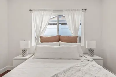 a bedroom with a bed with white sheets and a window at Luxury home w/ yard + parking in Newhall