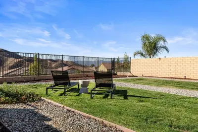 two chairs sitting in the grass next to a fence at Scenic Mountain View Home with Spacious Yard in Santa Clarita