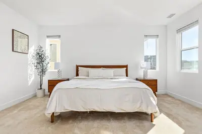 a white bedroom with a bed and two windows at Scenic Mountain View Home with Spacious Yard in Santa Clarita