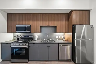 a kitchen with stainless steel appliances and wooden cabinets at Modern Getaway Heart of Long Beach in Long Beach