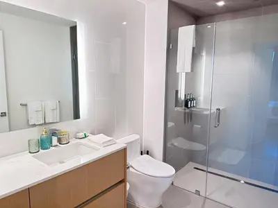 a bathroom with a toilet and a glass shower at Luxury 2BD 2BA with Roof Top Pool, Hot Tub & Gym in Los Angeles