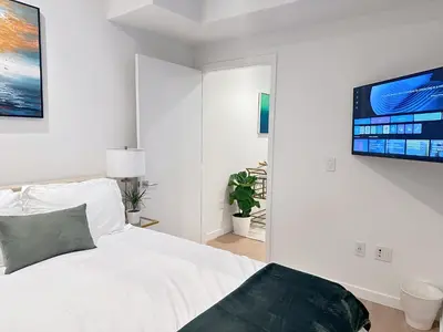 a white bedroom with a bed and a flat screen tv at Luxury 2BD 2BA with Roof Top Pool, Hot Tub & Gym in Los Angeles