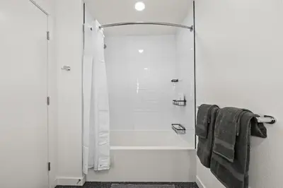 a white bathroom with a shower and a tub at Chic Downtown Stay Walk to Beach in Long Beach