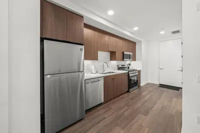 a kitchen with wooden cabinets and a stainless steel refrigerator at Chic Downtown Stay Walk to Beach in Long Beach