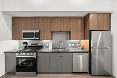 a kitchen with stainless steel appliances and wooden cabinets at Chic Downtown Stay Walk to Beach in Long Beach