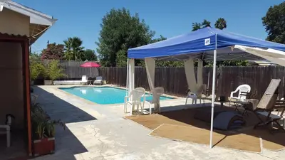 a blue umbrella and chairs next to a swimming pool at Hidden Gem In Plain Sight in Van Nuys Airport
