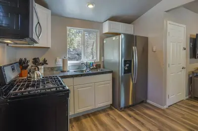 a kitchen with a stainless steel refrigerator and a sink at Cozy Forest Cottage w Lake Glimpse and Grill in Fawnskin