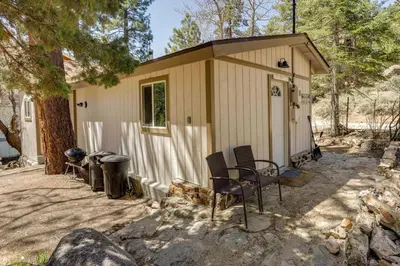 a small shed with chairs and a grill at Cozy Forest Cottage w Lake Glimpse and Grill in Fawnskin