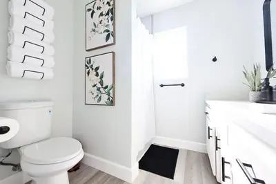 a white bathroom with a toilet and a sink at Family Friendly Southwest Bakersfield Retreat with Jacuzzi and Fenced Yard in Bakersfield