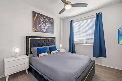 a bedroom with a large bed with blue curtains at Cozy 3 BR Apartment | Near Disney in Placentia