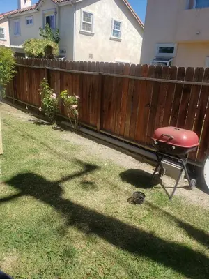 a grill in a yard next to a wooden fence at Spacious home near LAX in Hawthorne