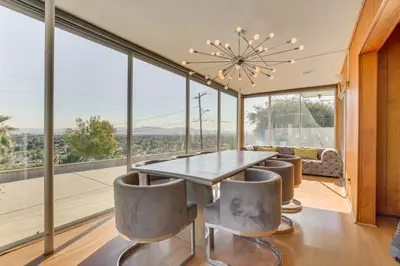 a dining room with a table and chairs and large windows at Stunning MCM Escape with Mtn Views in San Bernardino in San Bernardino