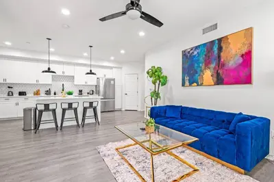 a living room with a blue couch and a kitchen at Newly Remodeled 3BR Apt | Mins to Disney | Arcade in Placentia