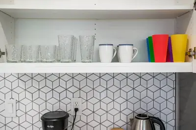 a shelf with cups and other items on it at Newly Remodeled 3BR Apt | Mins to Disney | Arcade in Placentia