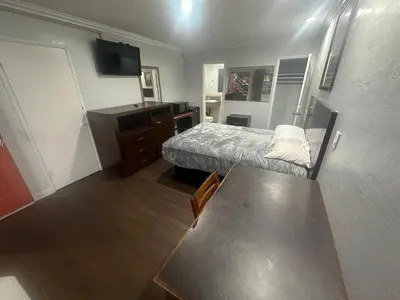 a small room with a bed and a desk at Heritage Inn in Pomona